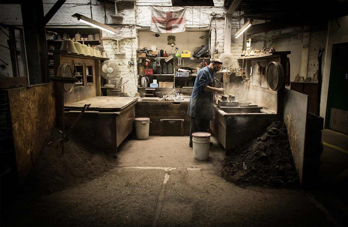 Photograph of a man working in an old character filled workshop making bells at the Whitechapel Bell Foundry, for Discover Britain - By Paris Penny Photography